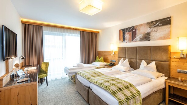 Een hotelkamer met een groot bed, een bureau, een stoel, een televisie en een schilderij aan de muur.