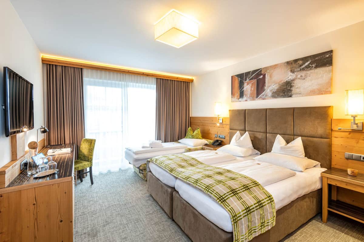 Una habitación de hotel con una cama grande, un escritorio, una silla, un televisor y un cuadro en la pared.