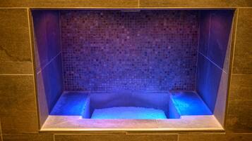 Relax in a serene bathtub area with a mosaic tile wall and stone accents.