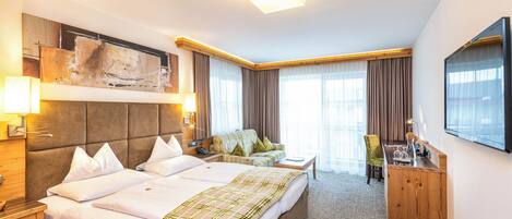 Una habitación de hotel con una cama grande, un sofá, un escritorio y un televisor.