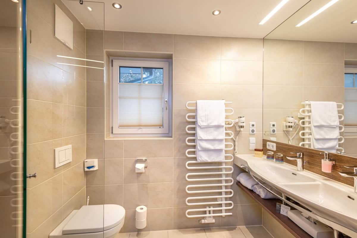 Un baño moderno con cabina de ducha de vidrio, inodoro, toallero y tocador con espejo.