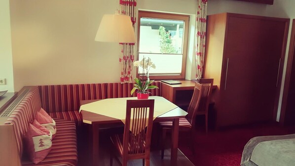 Un comedor con una mesa de madera, un sofá a rayas y sillas. Hay una planta en maceta sobre la mesa.