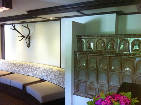 A reception area with a cushioned bench, a wall-mounted deer skull, and a decorative panel with glass panels. - Apart Hotel Garni Austria (Mayrhofen)