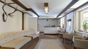 A spacious living area with a long bench, a dining table, and chairs. A deer skull is mounted on the wall.