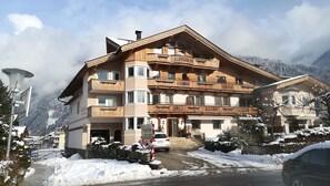 A multi-story hotel with wooden balconies, a ski lift in the background, and snow-covered surroundings. - Apart Hotel Garni Austria (Mayrhofen)