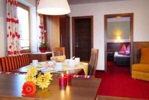 A hotel room with a dining area, a bed, and a red carpet. - Apart Hotel Garni Austria (Mayrhofen)