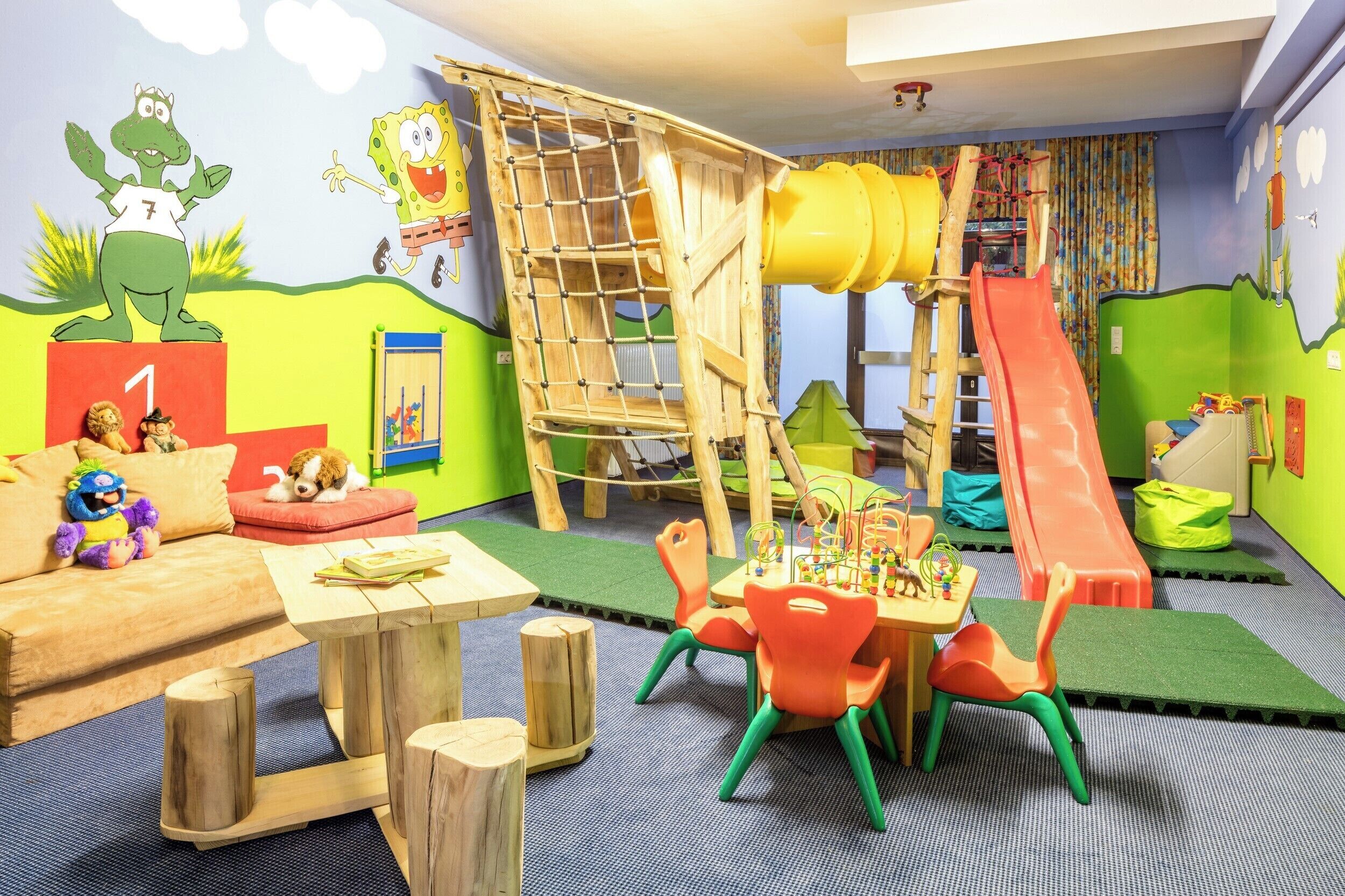 A children's playroom with a wooden play structure, a slide, and colorful furniture.