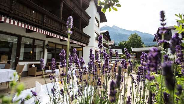 A restaurant with outdoor seating, surrounded by mountains and lavender plants. - Hotel Solstein (Seefeld in Tirol)