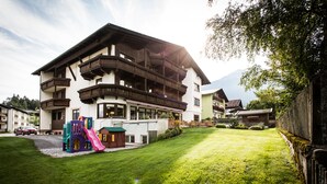 A large, multi-story building with balconies, a children's play area, and a well-maintained lawn. - Hotel Solstein (Seefeld in Tirol)