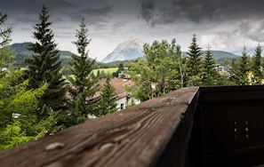 A mountain view with a wooden railing, surrounded by evergreen trees and houses. - Hotel Solstein (Seefeld in Tirol)