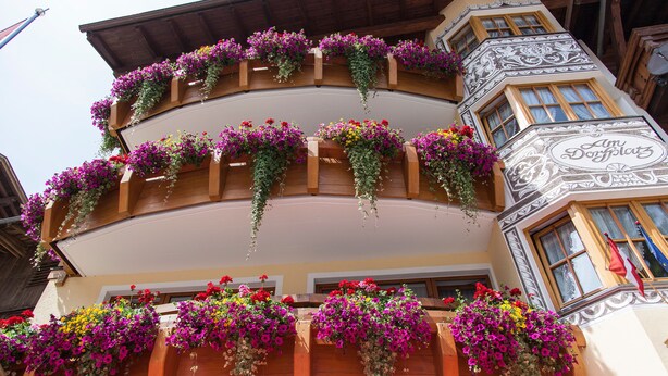 En byggnad med flera balkonger som är dekorerade med hängande blomkorgar.