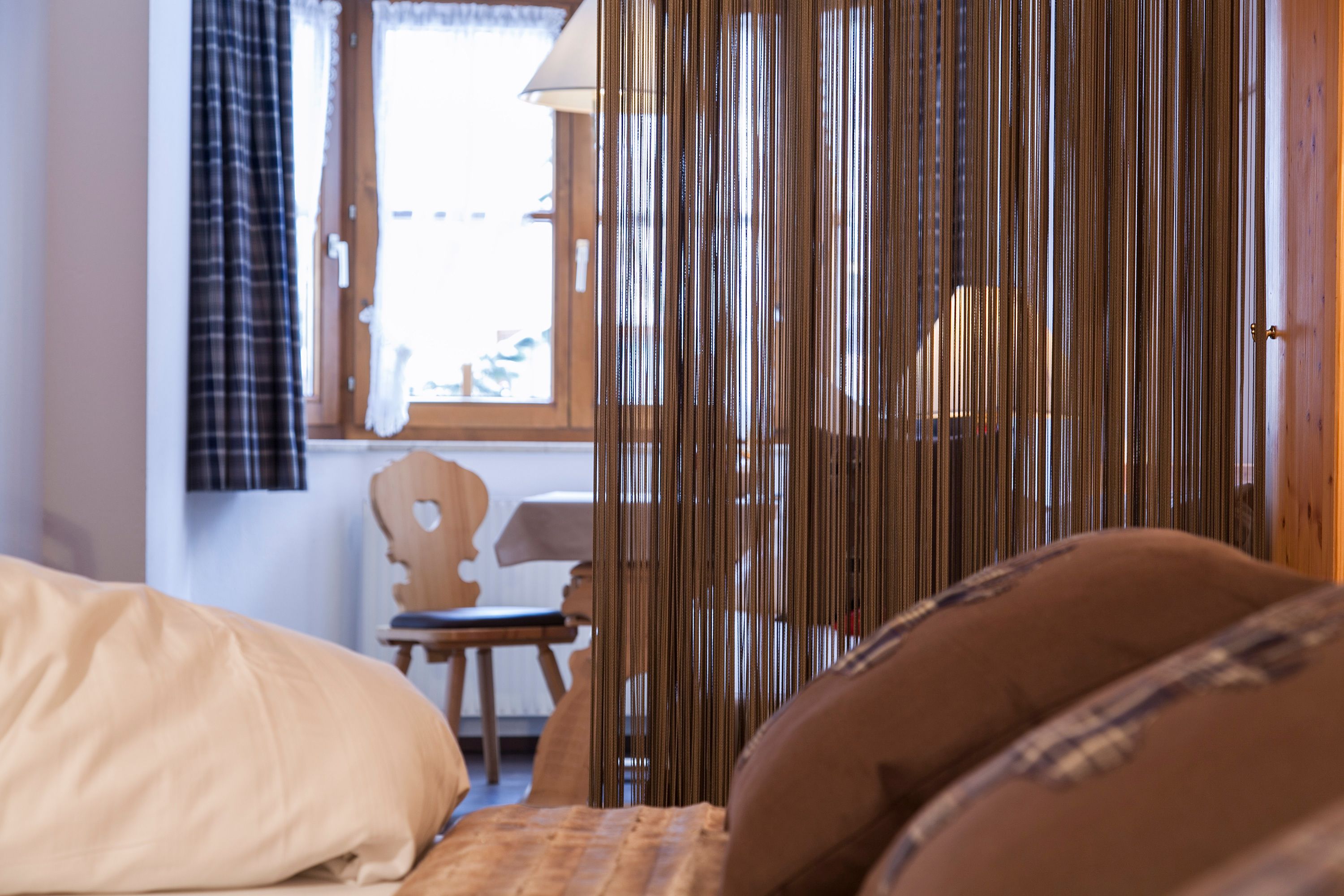 A hotel room with a bed, a chair, and a window with curtains.