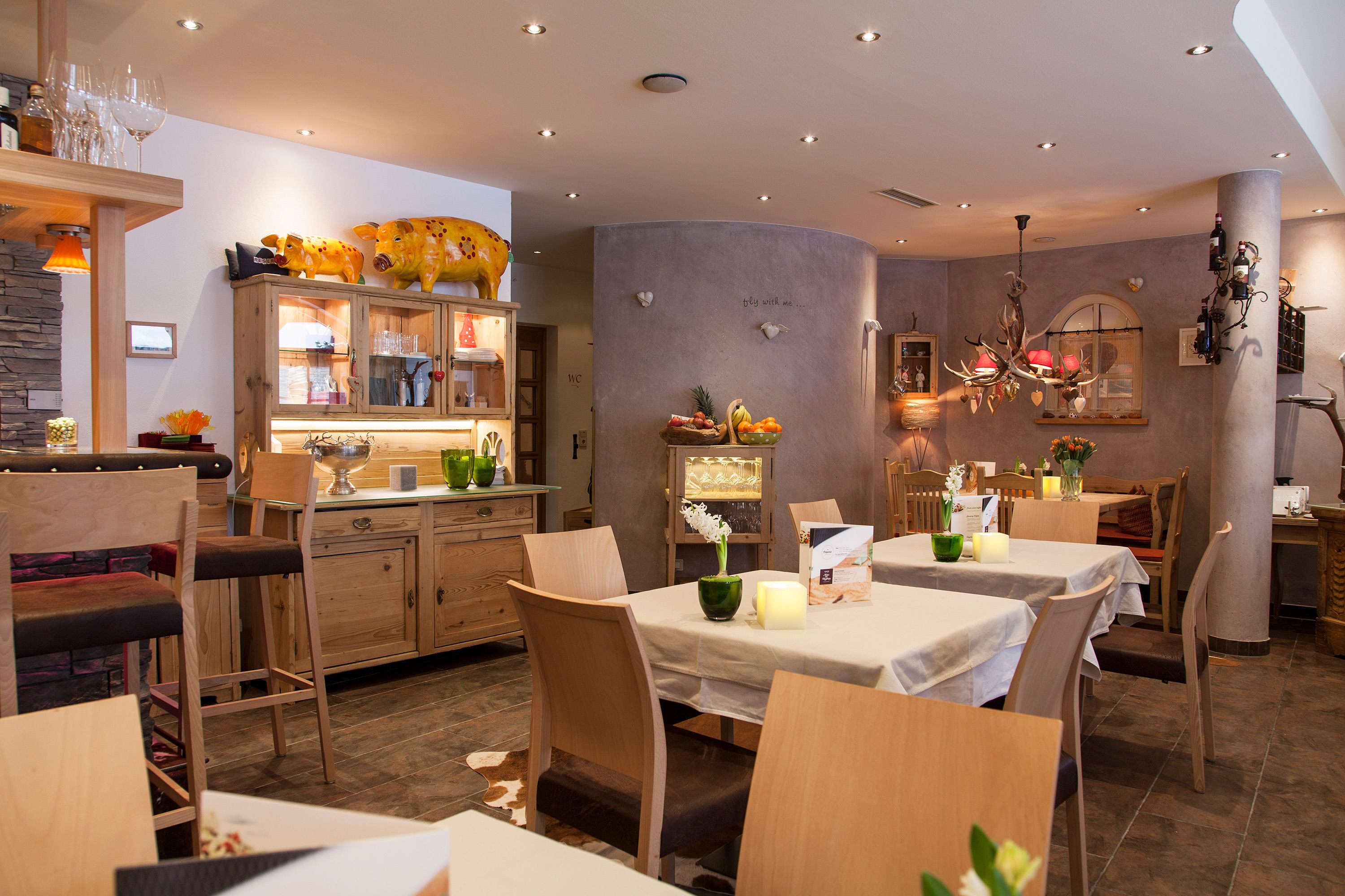 A restaurant with wooden furniture, a bar area, and a decorative wall with a fruit bowl and wall art.