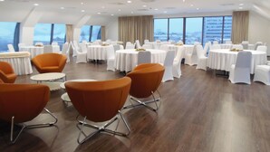 Un salón de conferencias con mesas y sillas redondas, ventanas amplias y un diseño moderno de techo.
