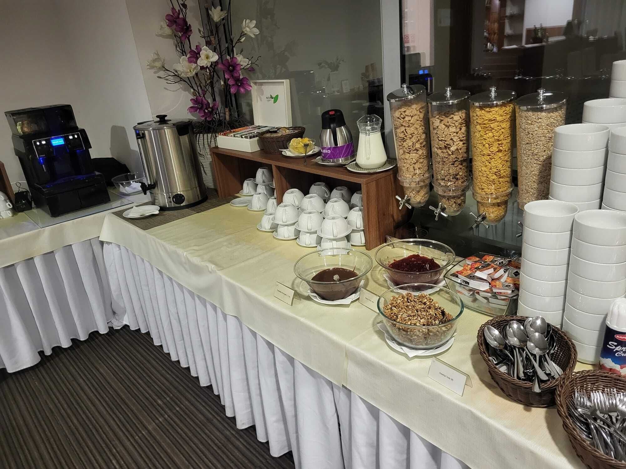 A buffet setup with various food items, utensils, and a coffee machine.