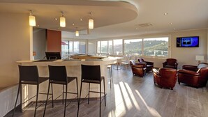 A modern kitchen with a bar area, large windows, and leather seating. - Hotel Carre Noir (Porto-Vecchio)