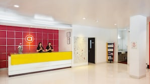 Un espace d’accueil avec un comptoir rouge et jaune, une carte accrochée au mur et un panneau indiquant qu’il est interdit de fumer dans la zone.