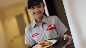 Une personne en uniforme tenant un plateau sur lequel se trouve un sandwich.