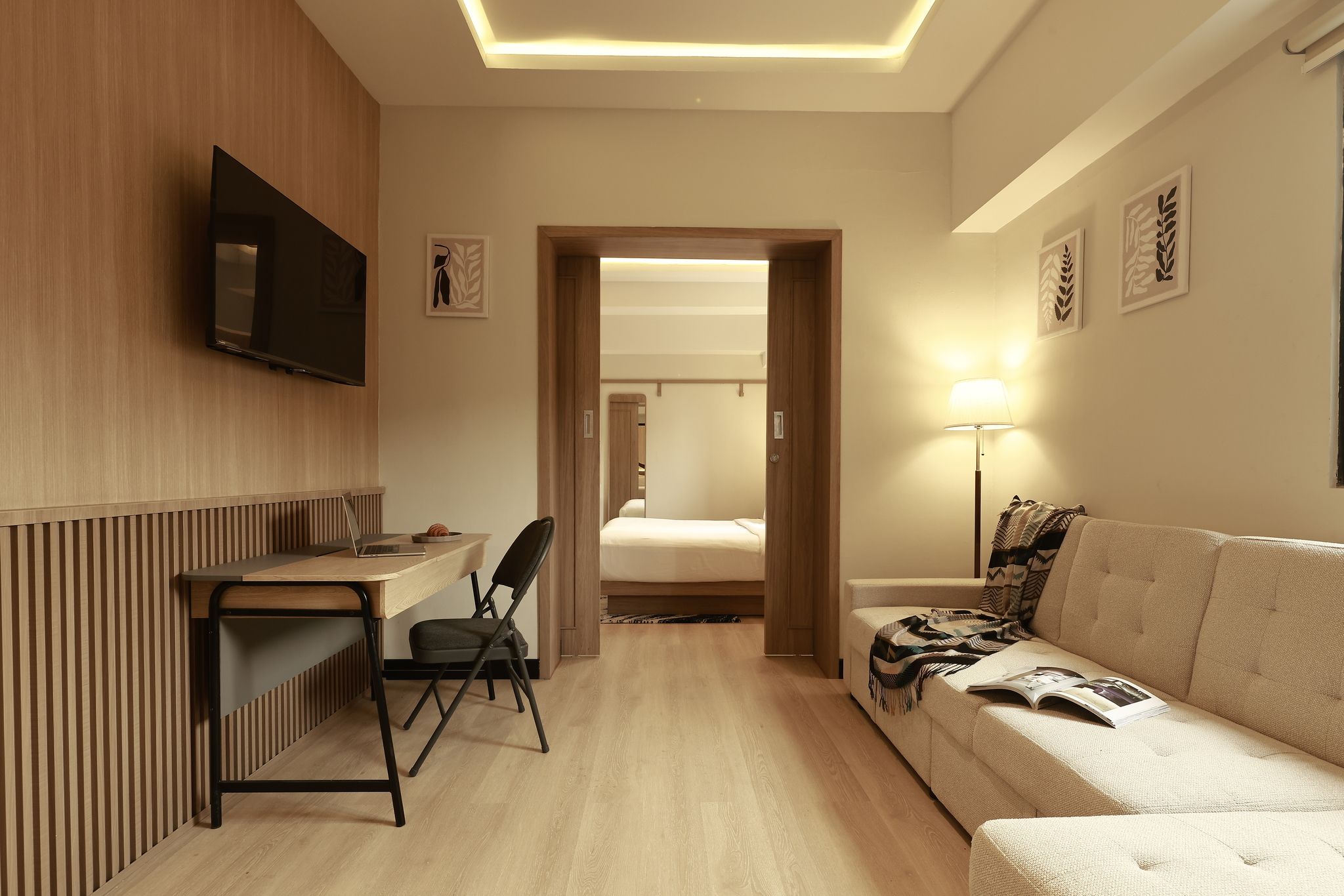 A hotel room with a desk, chair, bed, and a sofa.