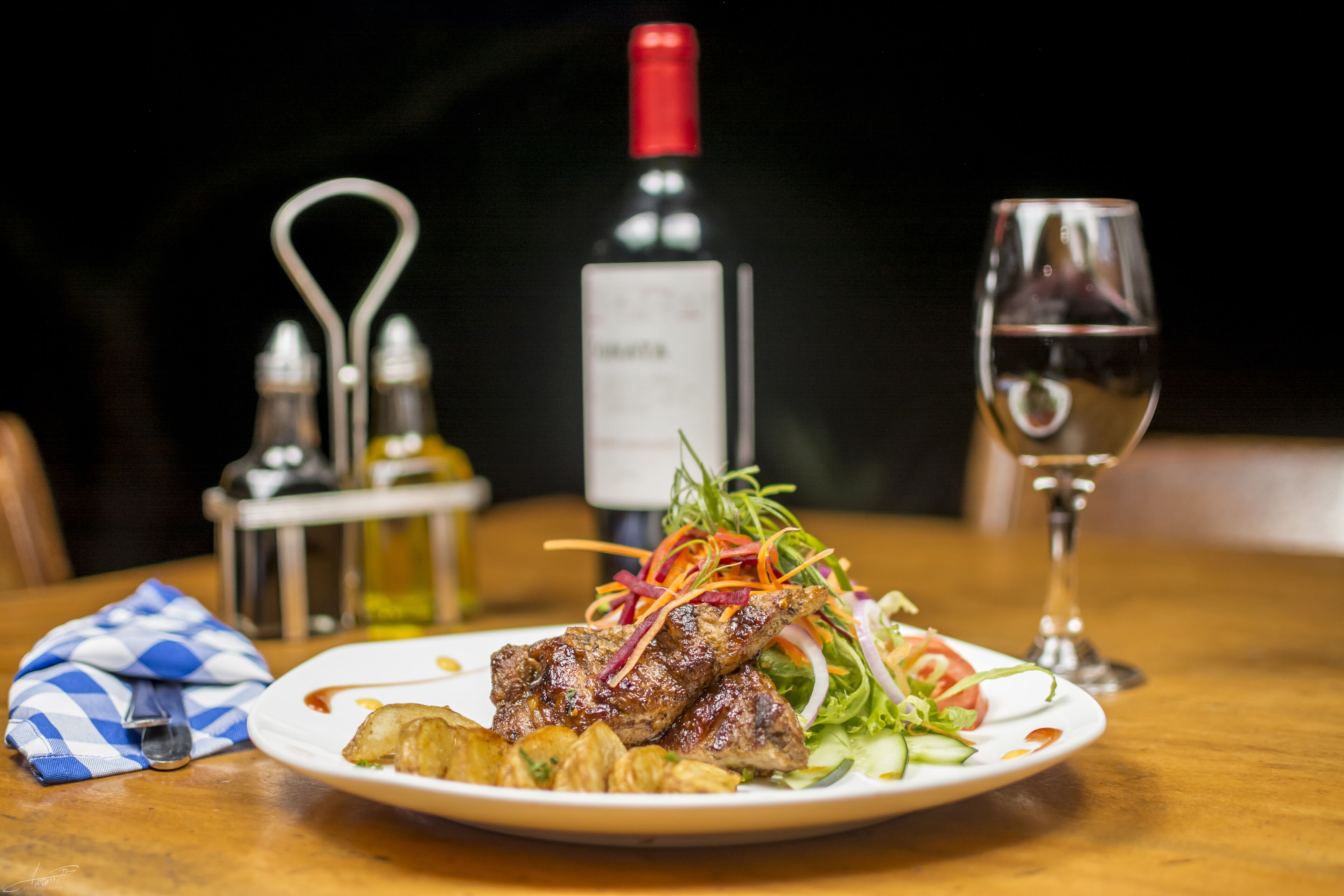 Un plato de comida con una botella de vino y una copa de vino sobre una mesa.