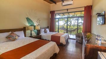 A hotel room with two beds, a desk with a mirror, a TV, and a large window with curtains.