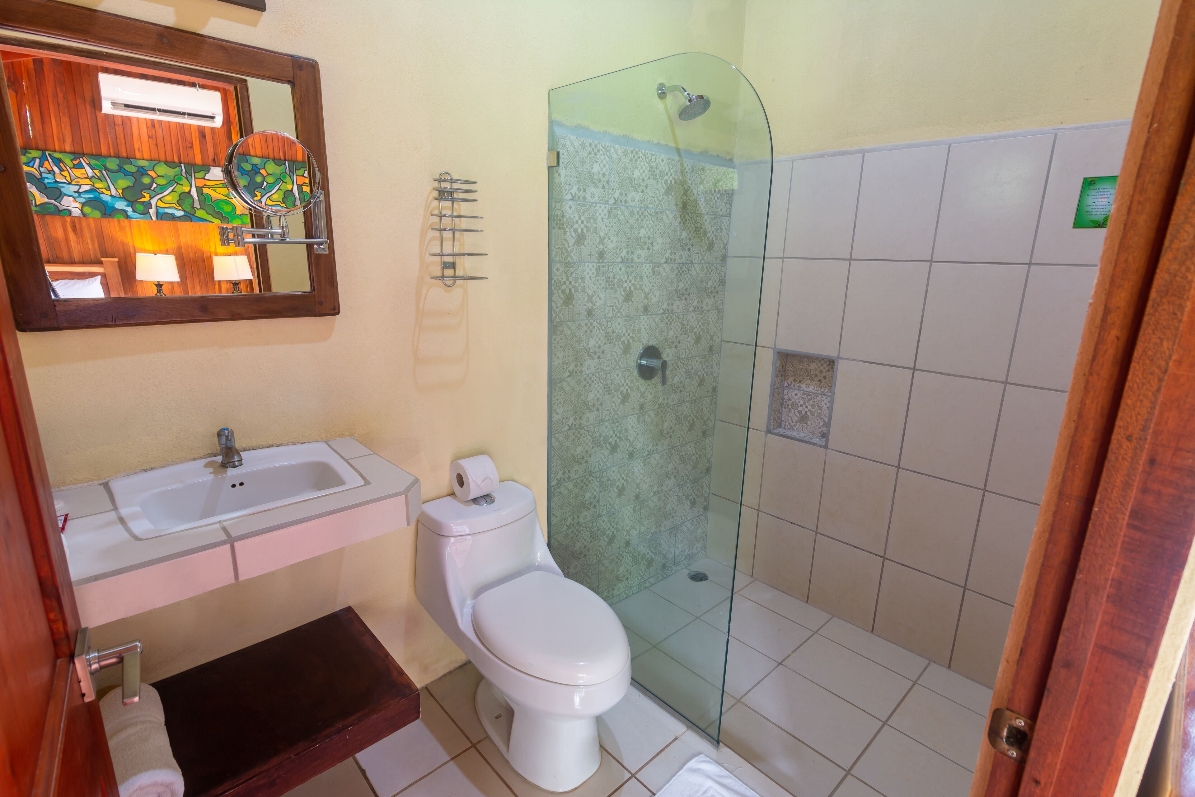 A bathroom with a white sink, toilet, and glass shower enclosure.