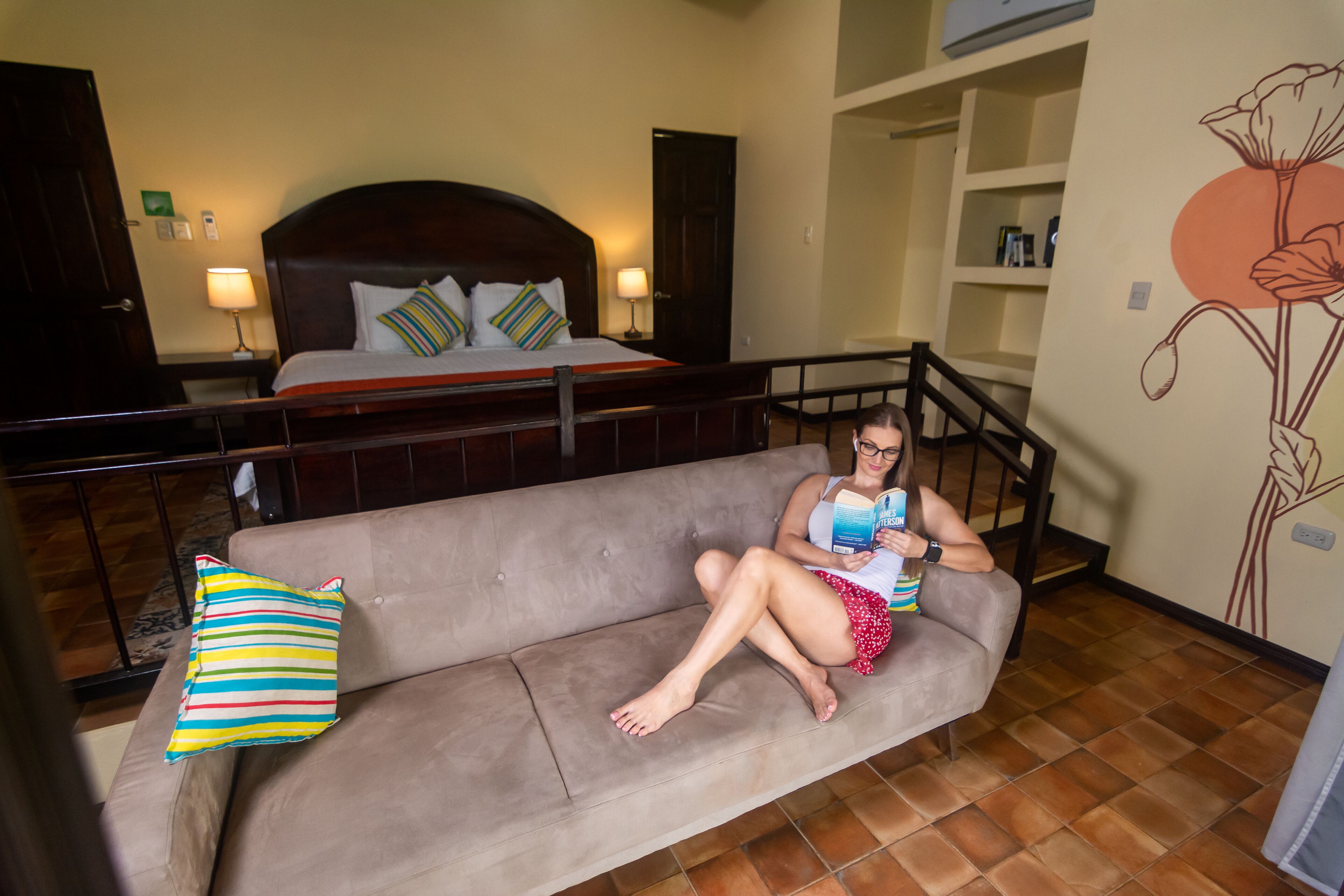 A room with a bed, a sofa, and a staircase.
