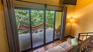 A room with a large sliding glass door leading to an outdoor deck with a hammock and a chair.