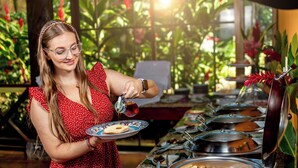A buffet setup with various food items and a person serving food.