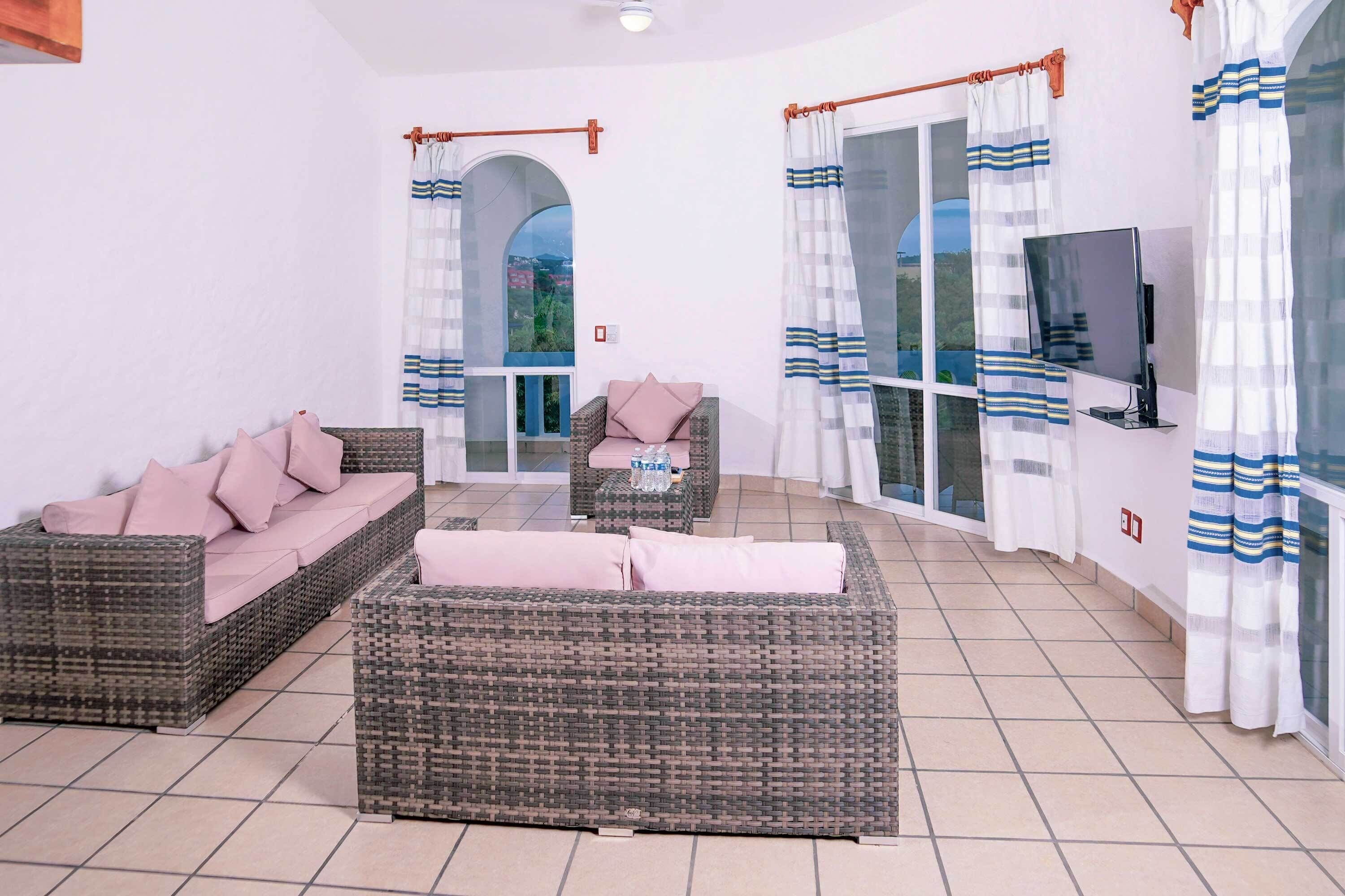A spacious patio with wicker furniture, a TV, and curtains.