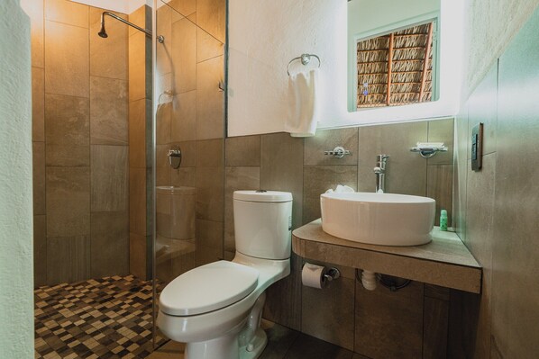 Un baño con ducha, inodoro, lavabo y un perchero para toallas.
