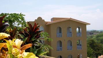 A building with multiple arched windows and a balcony, surrounded by lush greenery.