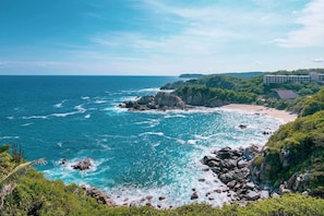A coastal hotel with a beach view, rocky shoreline, and lush greenery. - Villas & Resort Luz de Luna (Santa María Huatulco)