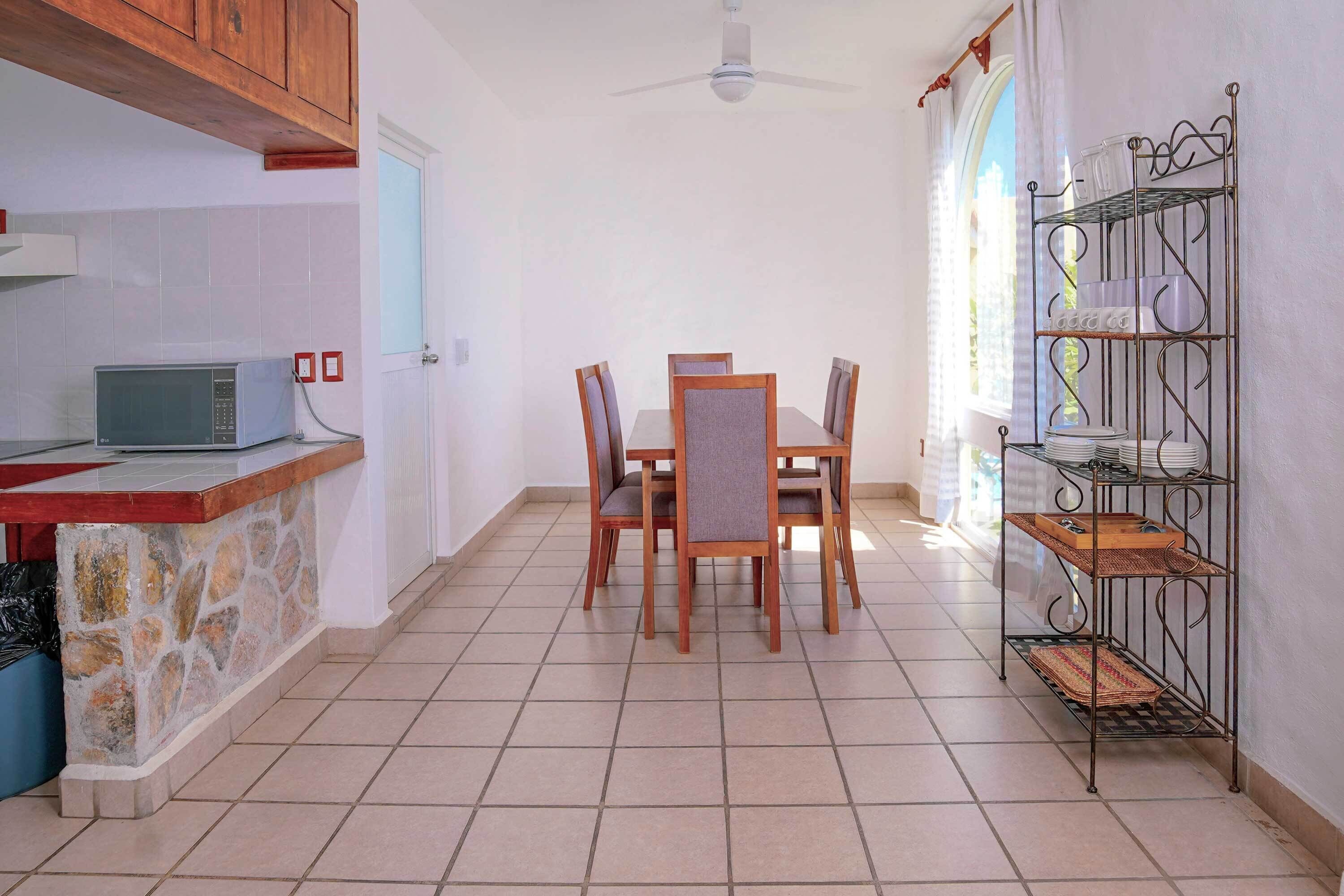 A kitchen with a stone countertop, a microwave, and a dining area with a table and chairs.