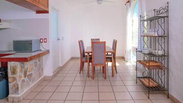 A kitchen with a stone countertop, a microwave, and a dining area with a table and chairs.