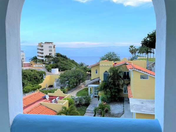 Zona residencial con vista al mar, con casas de tejados rojos y un edificio con balcones.