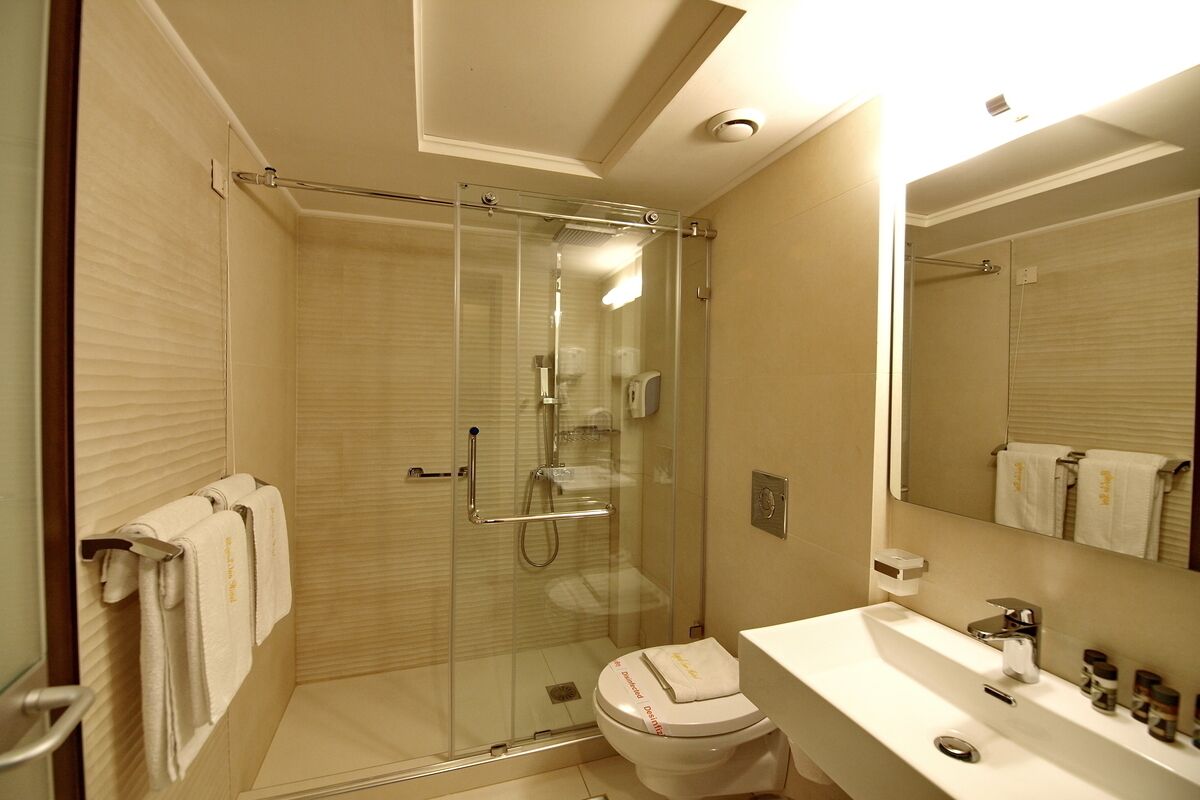 A modern bathroom with a glass-enclosed shower, a white sink, and a large mirror.