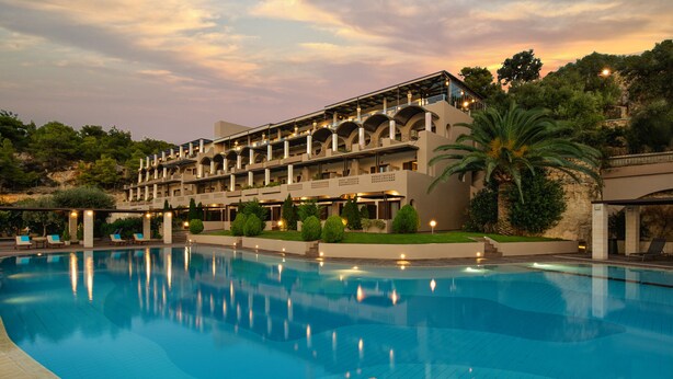 A hotel with a large swimming pool, multiple balconies, and lush landscaping. - Royal Sun Hotel (Chania)