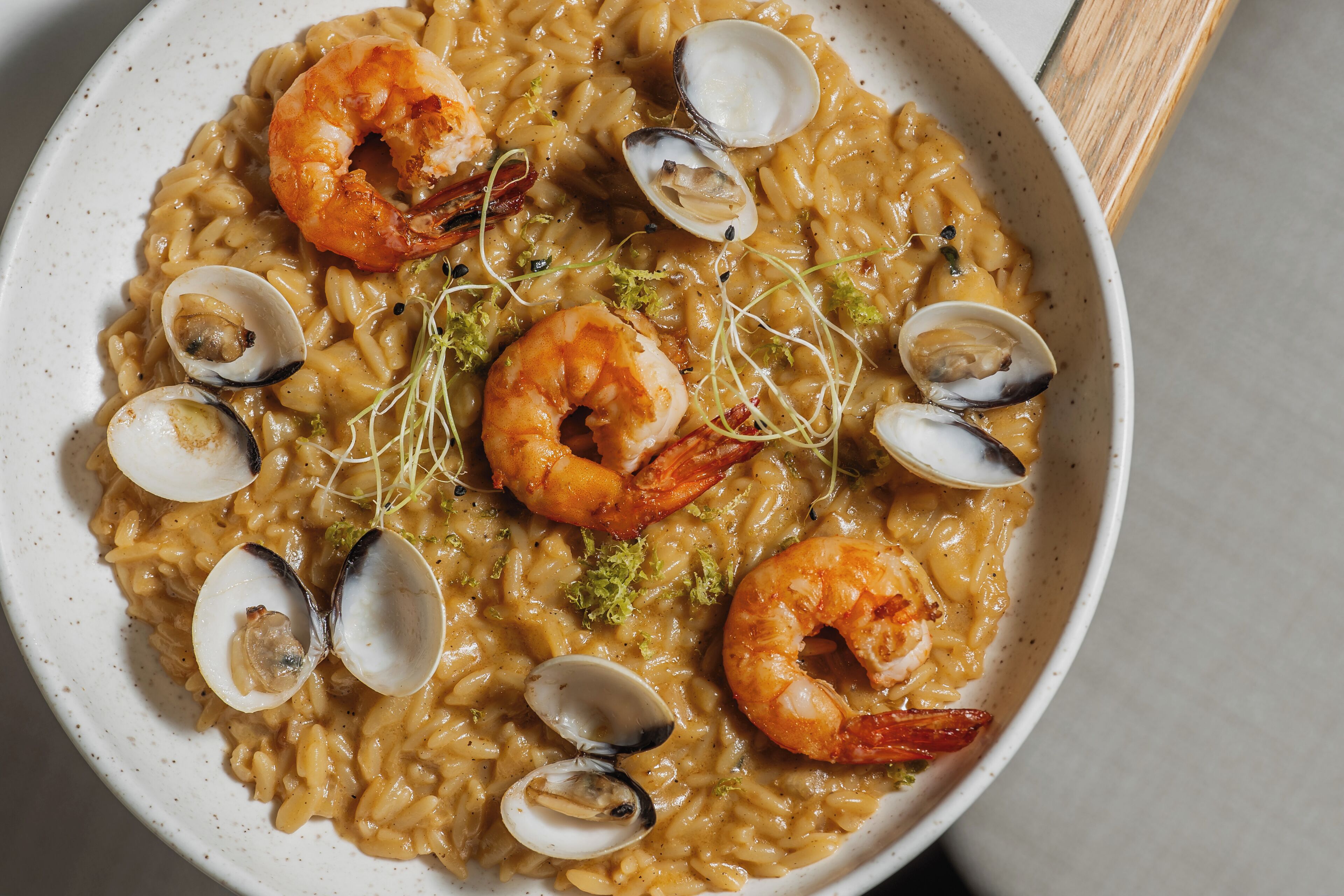 A bowl of seafood risotto with clams and shrimp.