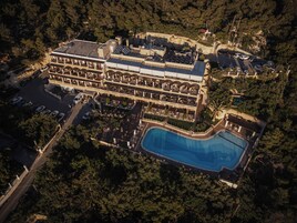 Μια αεροφωτογραφία ενός θέρετρου με μια μεγάλη πισίνα, πολλά μπαλκόνια και έναν χώρο στάθμευσης.