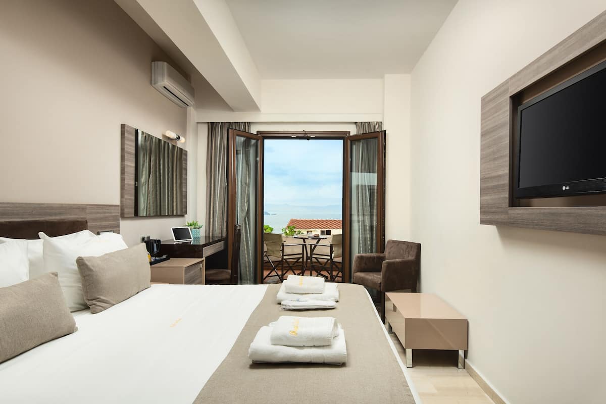 A modern hotel room with a large bed, a desk, a chair, and a TV.