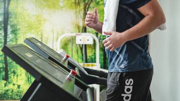 A treadmill in a gym with a forest mural in the background.