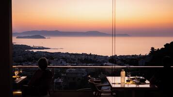 Un balcón con vista a un paisaje urbano y al mar al atardecer.