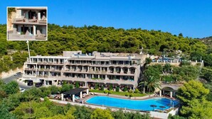 A multi-story hotel with a swimming pool, surrounded by lush greenery and a hilly landscape. - Royal Sun Hotel (Chania)