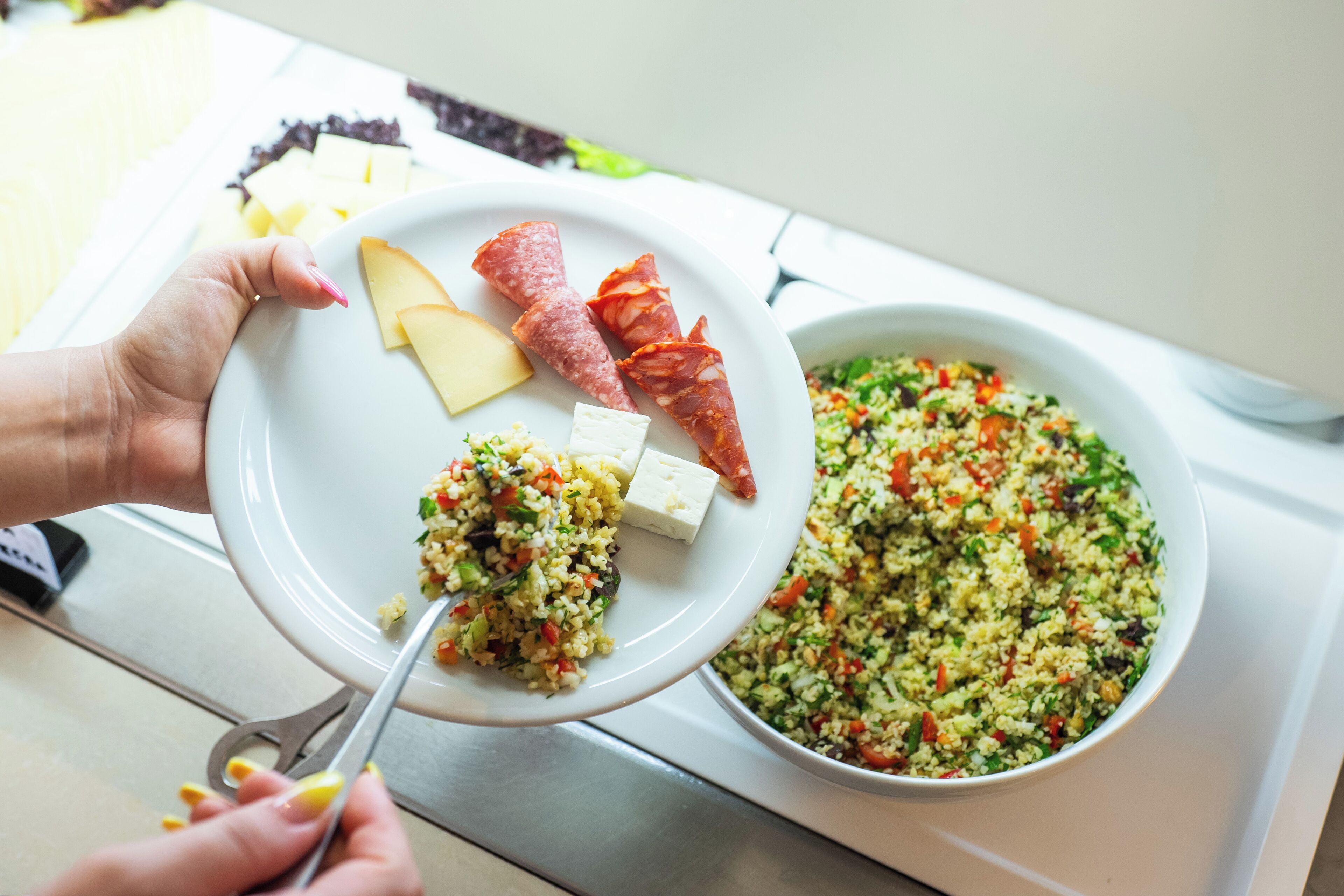 A plate with cheese, salami, and a bowl of salad.