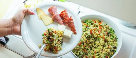 A plate with cheese, salami, and a bowl of salad.