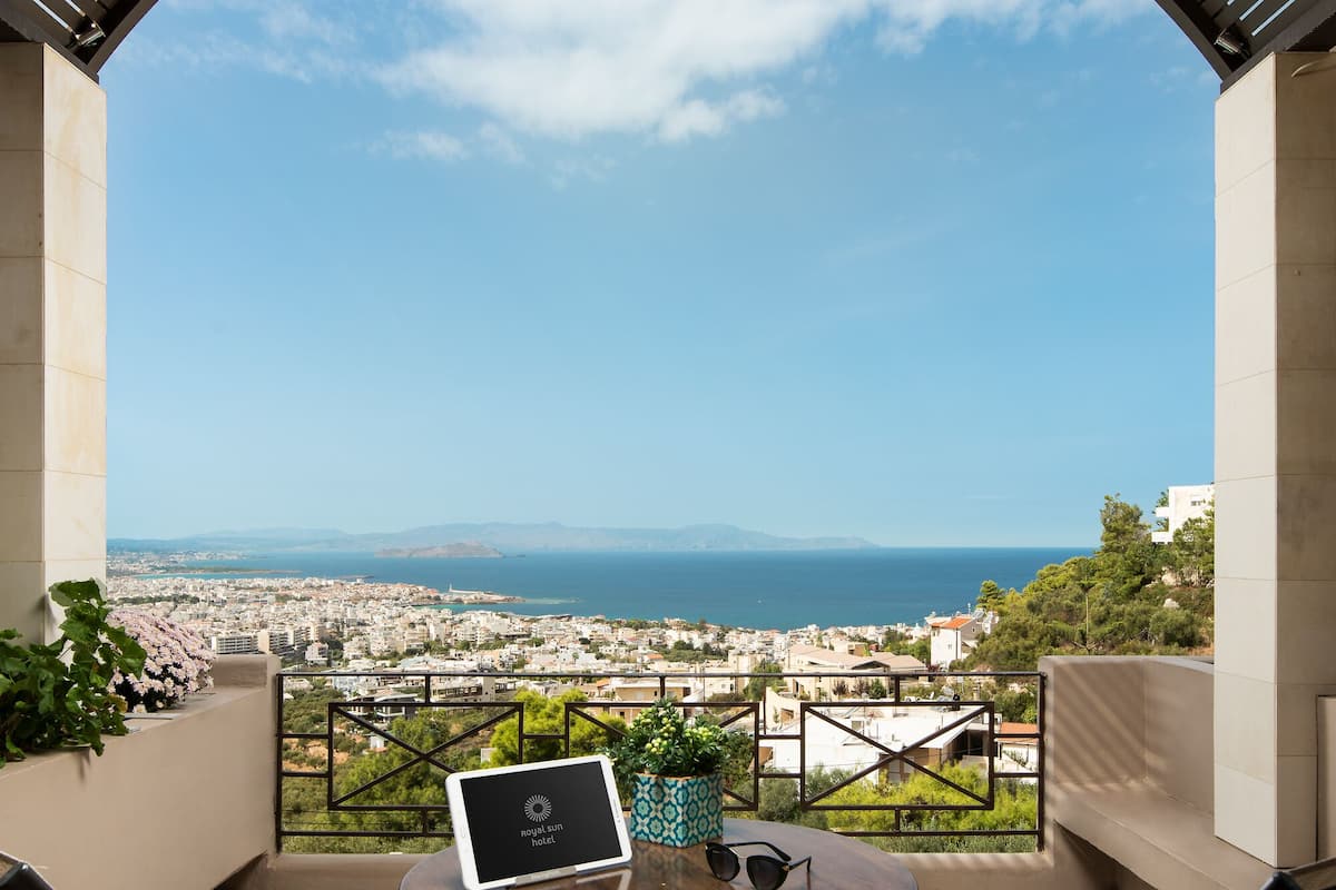 A terrace with a table and chairs, overlooking a cityscape and the sea.