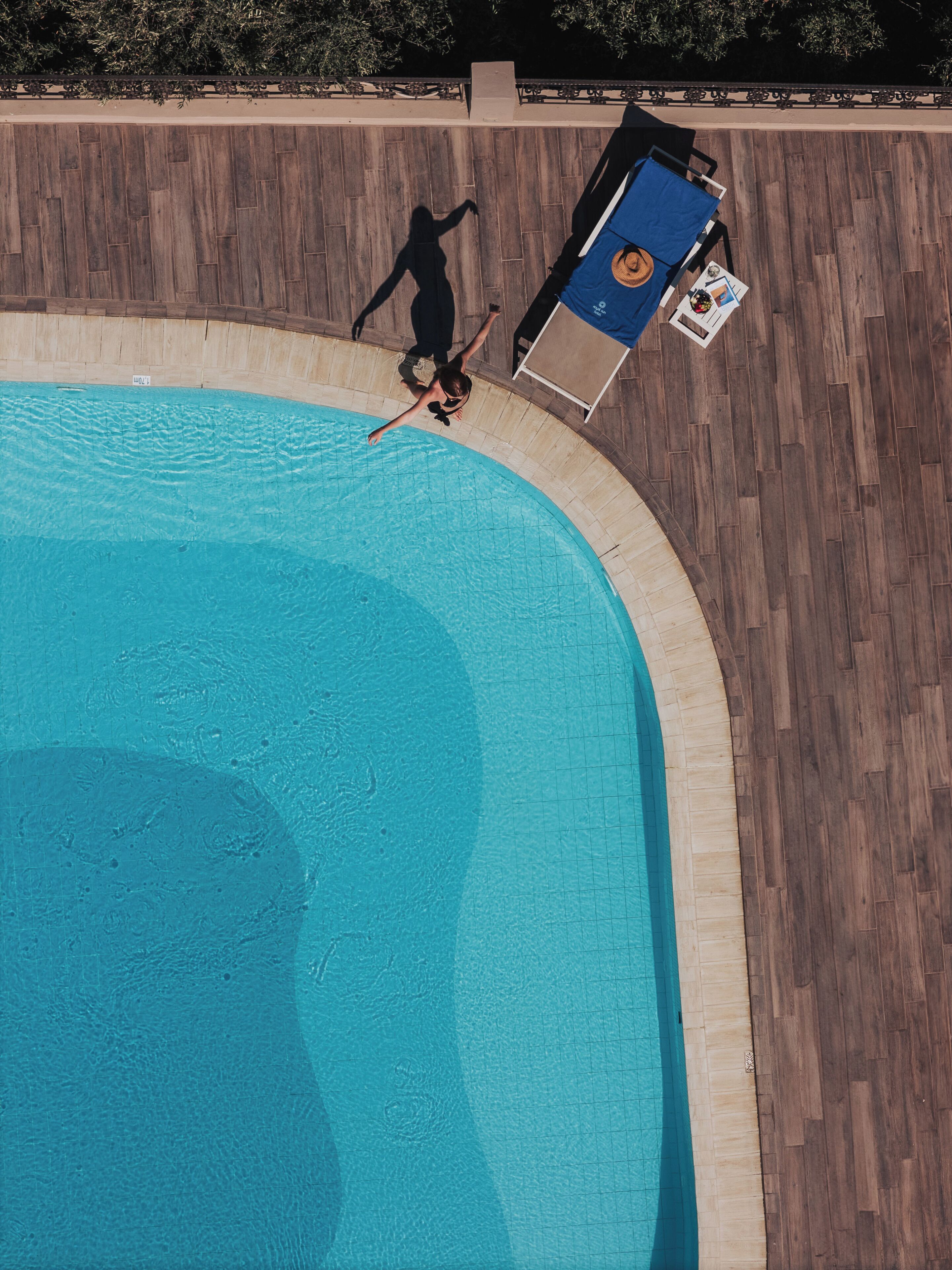 An aerial view of a swimming pool with a wooden deck surrounding it.