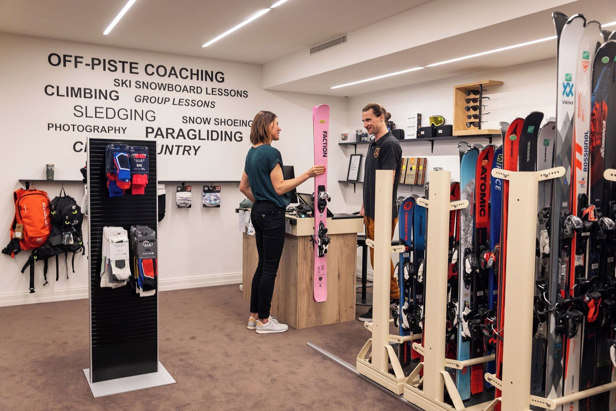 Tienda de equipo de esquí con un cartel que anuncia diversas clases de esquí y entrenamientos para fuera de pista.