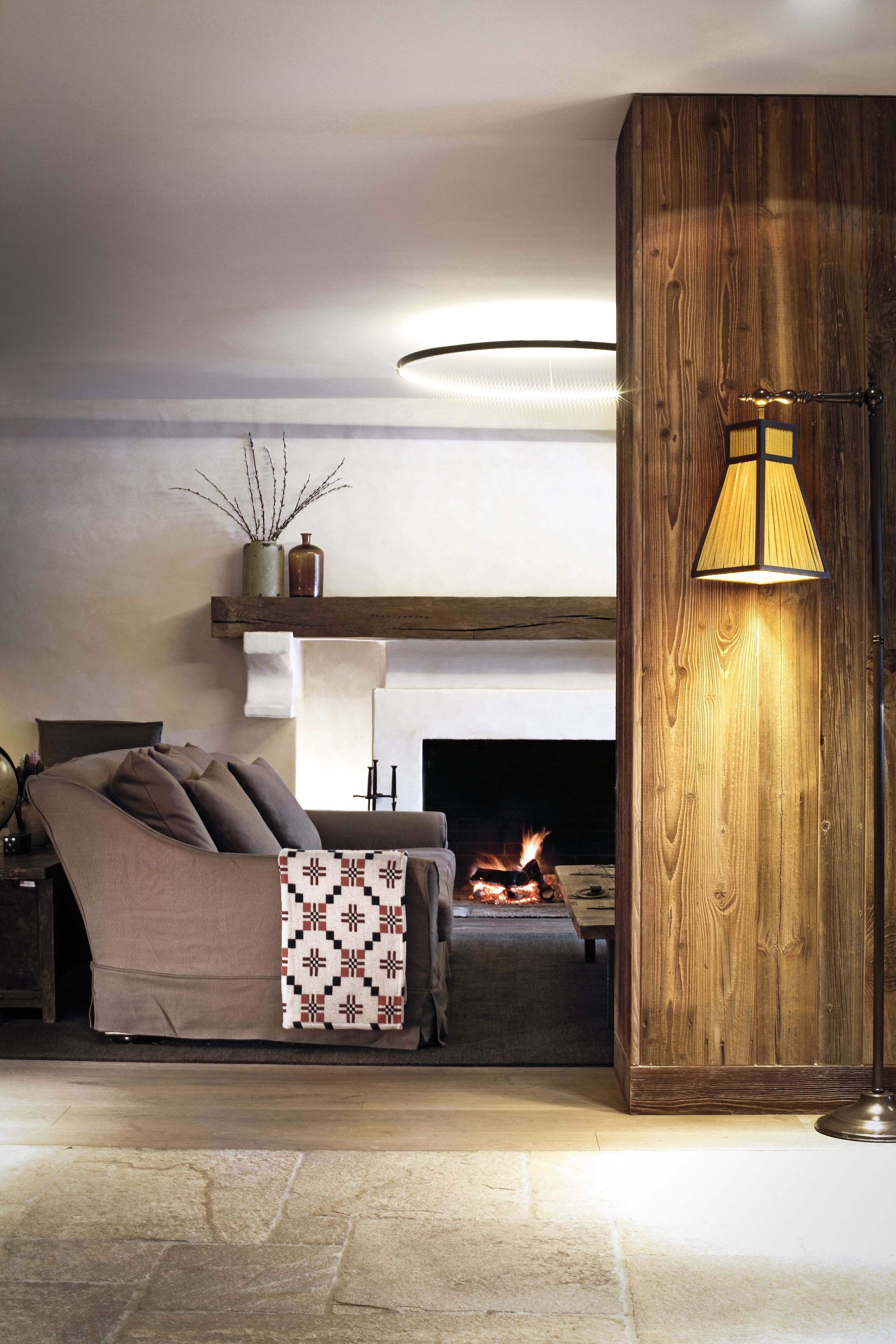 Un salon chaleureux avec une cheminée, un canapé, une table basse et une lampe.
